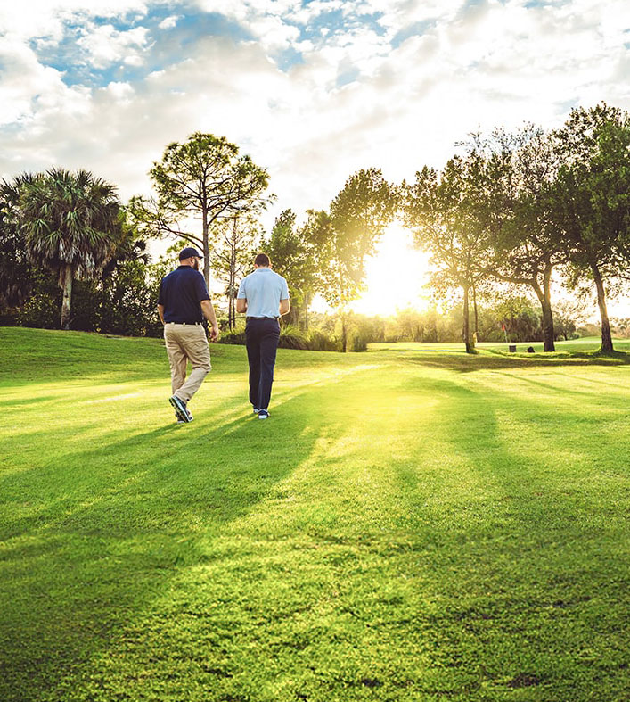 Two men walking on turf.